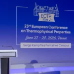 Une personne debout derrière un puptre dans un auditorium, a côté d'une présentation powerpoint intitulé "ECTP 2026"
