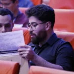 Deux personnes dans un auditorium regardant un programme papier